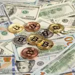 Bitcoins em cima de dinheiro de papel. Foto: Pexels