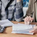 Calculadora e boletos em cima de uma mesa. Foto: Pexels