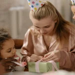 Mãe abre presente ao redor dos filhos. Foto: Pexels