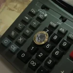 Calculadora com moeda de R$ 1 em cima. Foto: Marcello Casal Jr/Agência Brasil