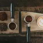 Grãos e xícara de café sobre tábua de madeira. Foto: Pixabay