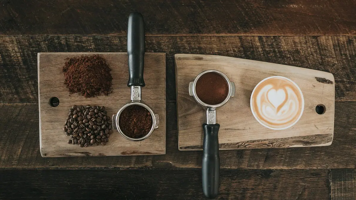 Grãos e xícara de café sobre tábua de madeira. Foto: Pixabay