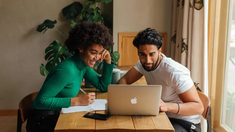 Casal em frente a computador com contas ao lado. Foto: Pexels