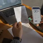 Mãos seguram conta e celular. Foto: Freepik