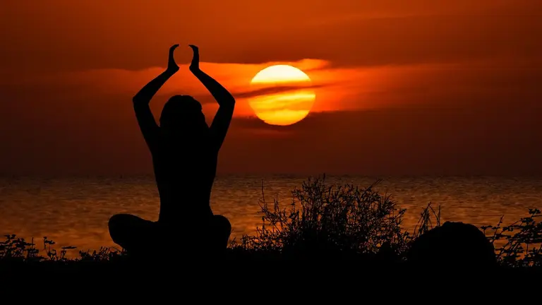 Mulher fazendo yoga ao pôr-do-sol. Foto: Pixabay