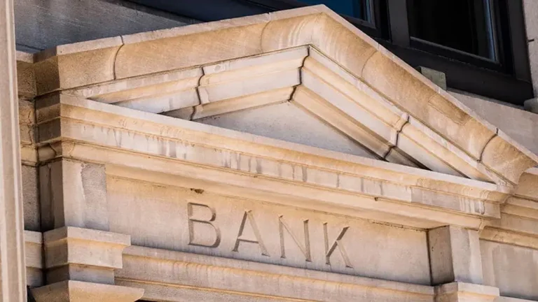 Fachada de pedra com a palavra Banco gravada. Foto: Adobe Stock