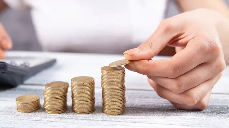 Mulher de negócios empilhando moedas. Foto: Adobe Stock