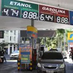 Cartazes mostram o preço da gasolina e do etanol em posto onde um carro é abastecido