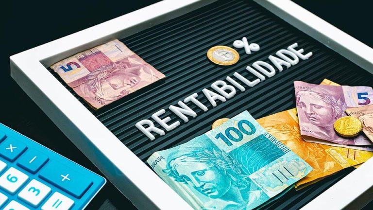 Notas de dinheiro e moedas sobre um letreiro em que a palavra rentabilidade está escrita